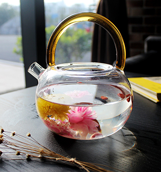 théière et tasse en verre avec fleur de thé en fleurs à l